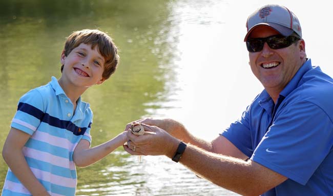 Father and son smiling in front of a pond