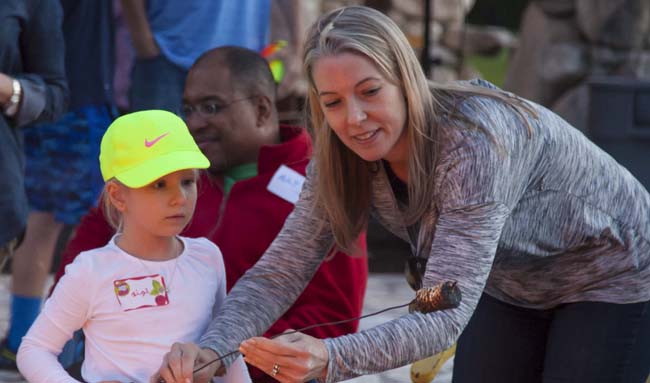 A lady helping a kid roast s’mores